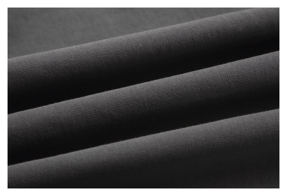 Close-up of dark charcoal fabric folded into soft ridges, showing its knit texture.