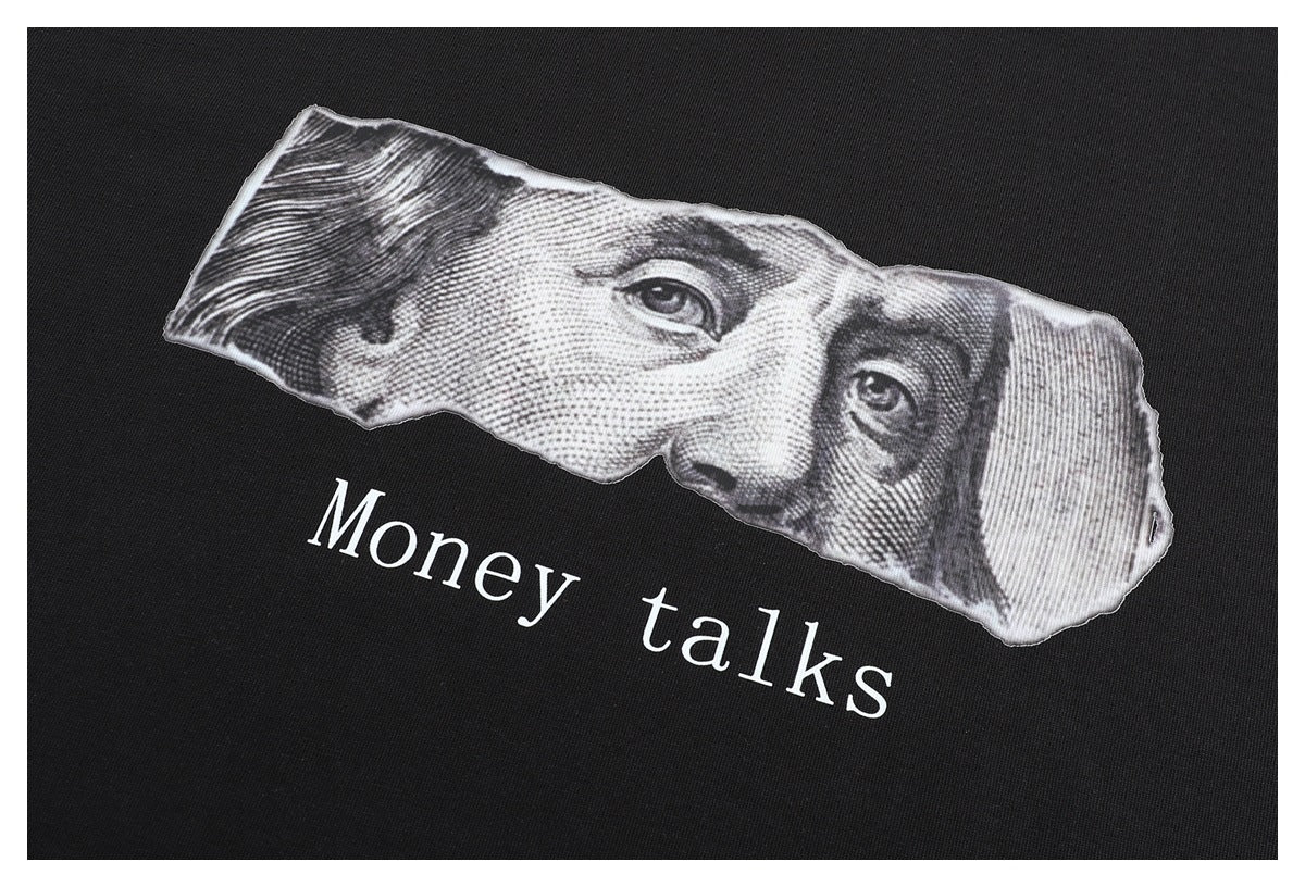Close-up of the T-shirt's grayscale banknote graphic and the white words “Money talks.”