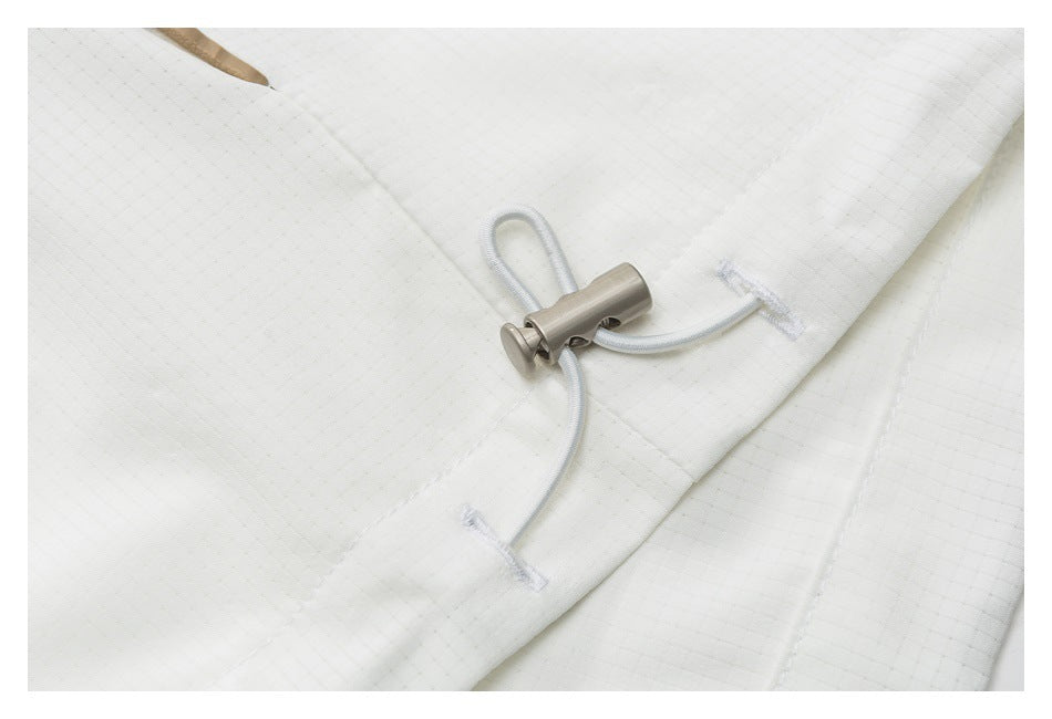 Close-up of a white drawcord threaded through a metal toggle on grid-textured fabric.