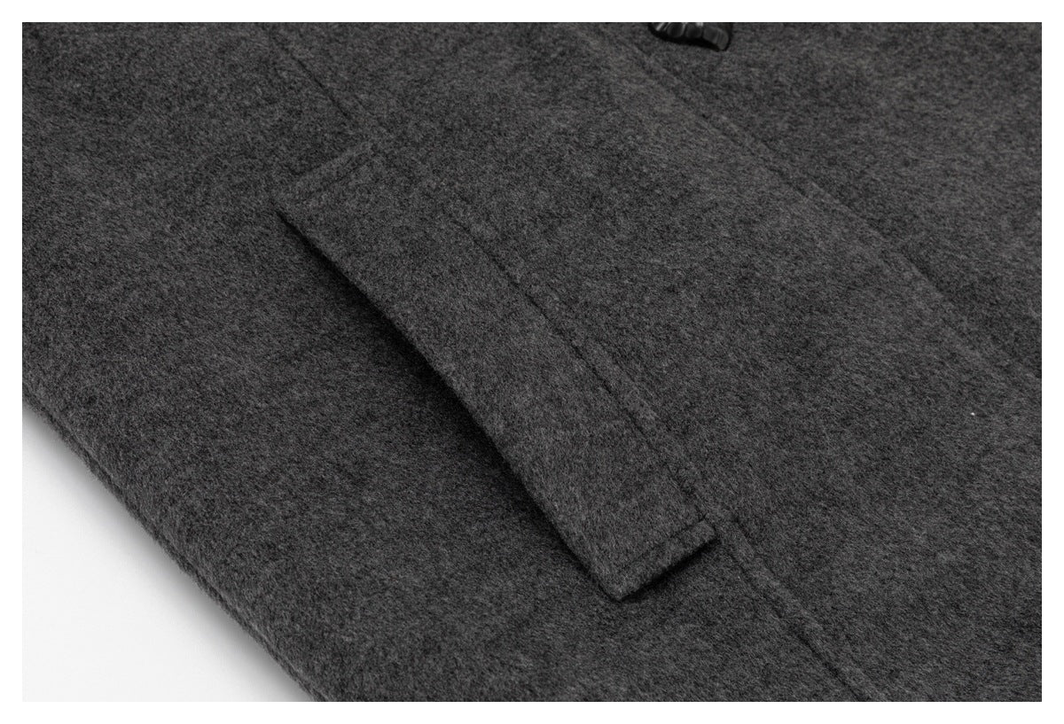 Close-up of a dark charcoal coat's angled welt pocket and a black button.