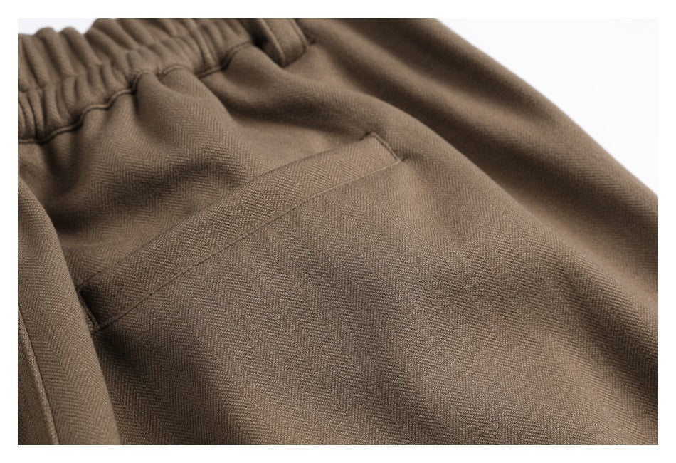 Close-up of a slanted pocket on taupe trousers, with the elastic waistband partly visible.