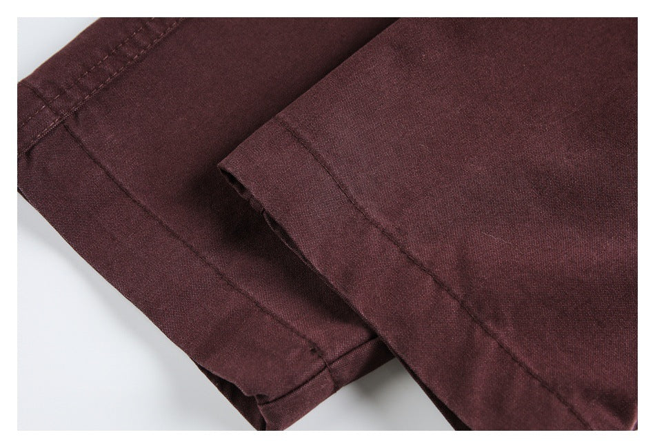 Close-up of burgundy fabric with a folded edge and parallel stitching.