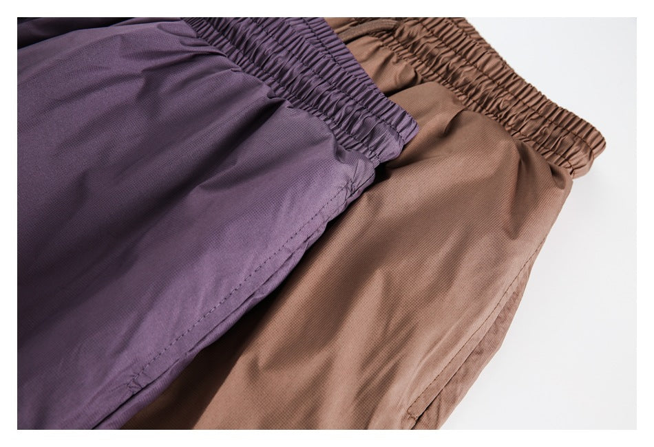 Close-up of plum-purple and brown shorts, showing the waistbands, fabric, and stitching.