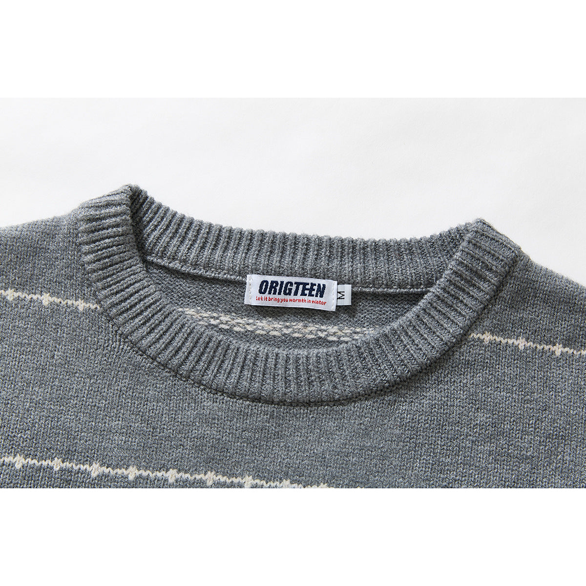Close-up of a gray knit sweater's ribbed crew neck, cream stripe, and sewn-in neck label.