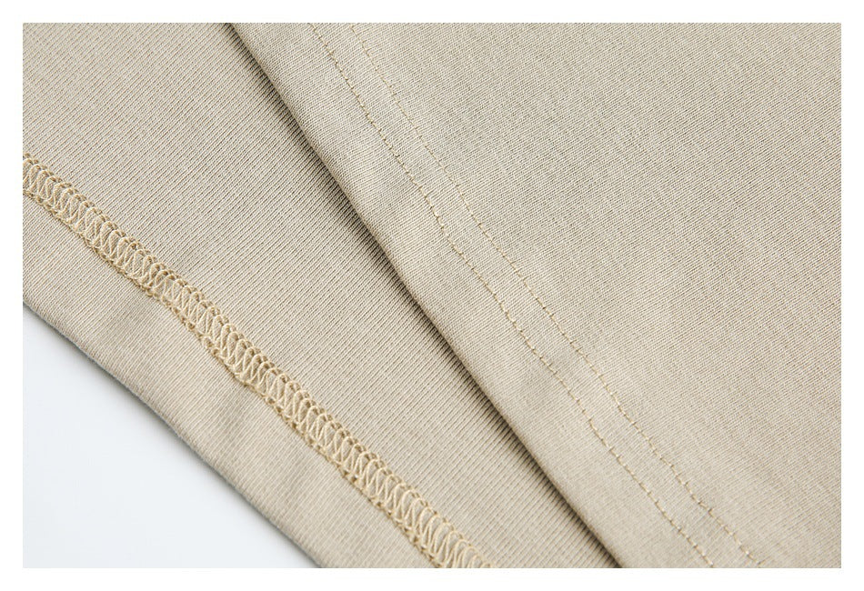 Close-up of beige garment fabric showing an overlocked seam and parallel stitching.
