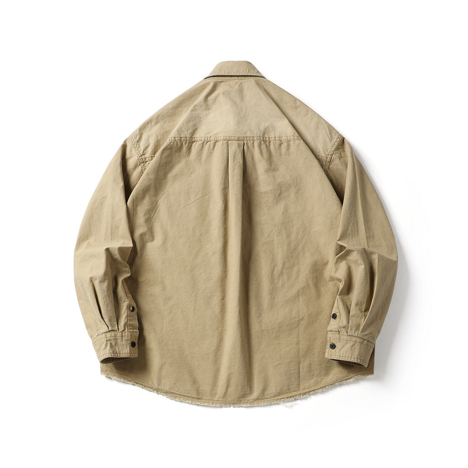 Back view of a tan long-sleeve button-up shirt laid flat, with a back yoke, center pleat, button cuffs and frayed hem.