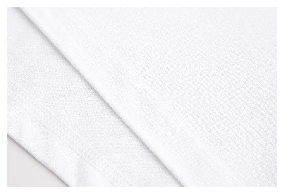 Close-up of white T-shirt fabric with stitched seams and an overlocked edge.