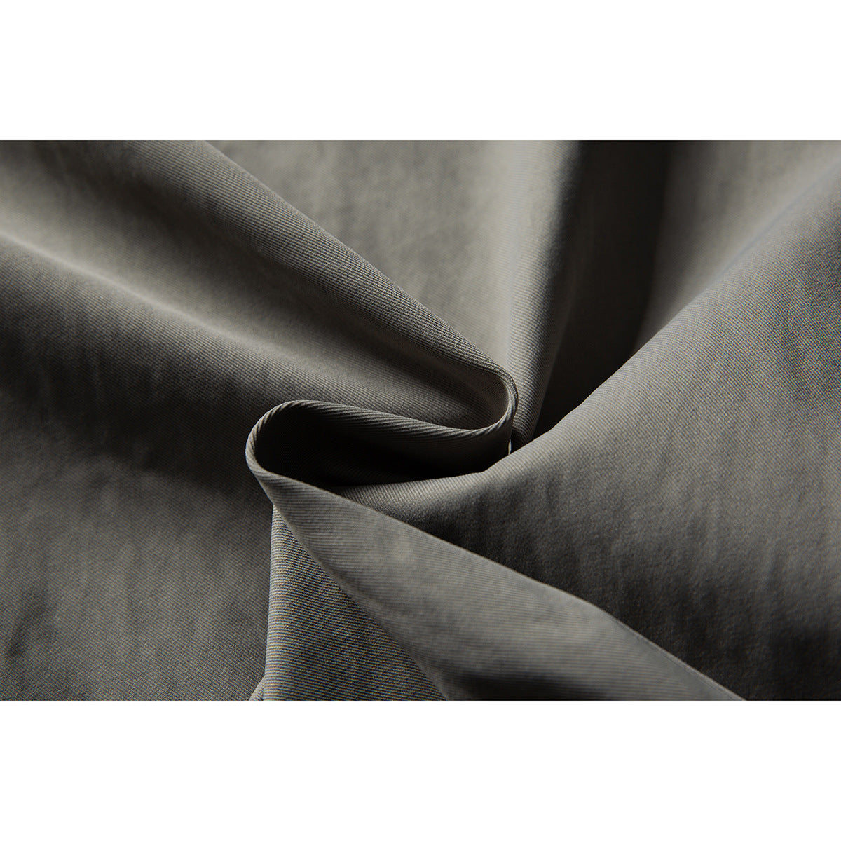 Close-up of gray fabric arranged in soft folds, showing its fine woven texture.