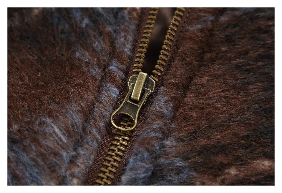 Close-up of a brass zipper against fuzzy brown-and-blue plaid jacket fabric.