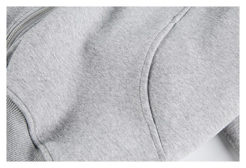 Close-up of a heather-gray garment with a silver zipper, ribbed edge and curved seam.