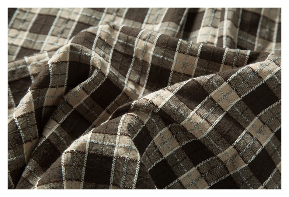 Close-up of gathered folds in a brown, beige, and gray plaid garment.