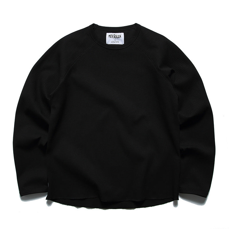 Front view of a black long-sleeve waffle-knit crewneck shirt with raglan seams.
