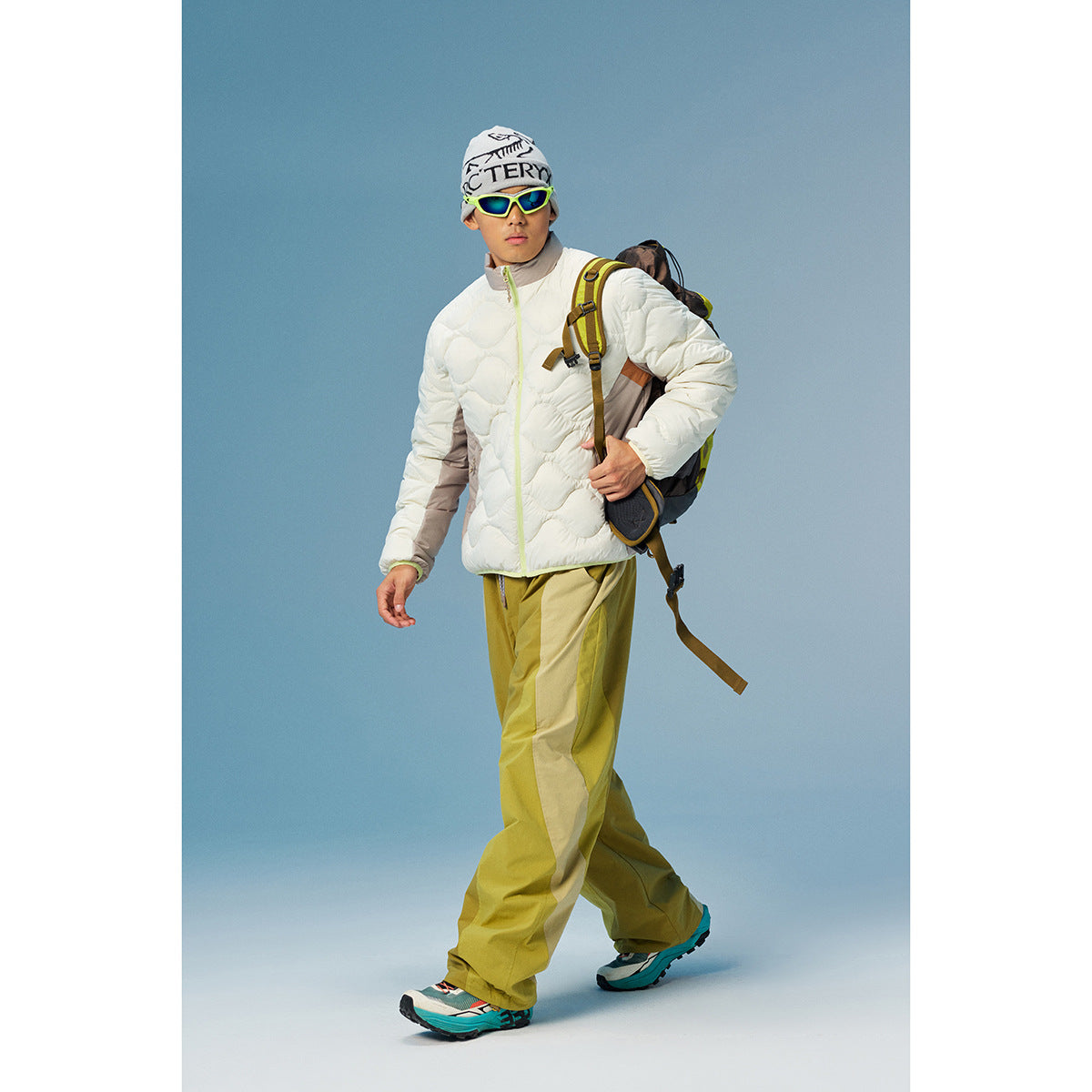 Model wearing a white quilted zip jacket with taupe sleeves and yellow-green trousers.