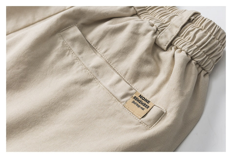 Close-up of beige trousers showing a pocket and a small sewn English-text label.