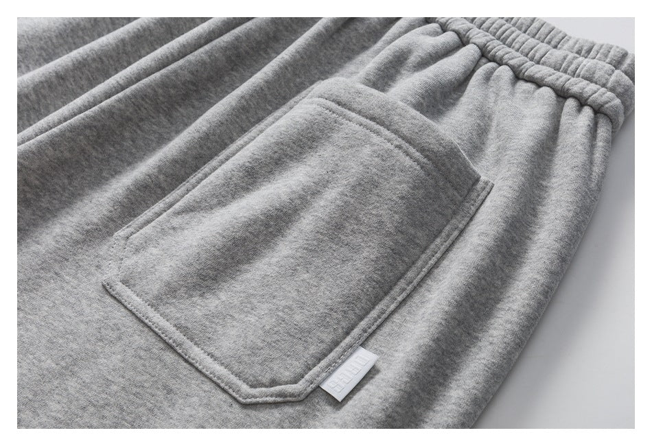 Close-up of a gray pants pocket, elastic waistband, and small white logo tab.