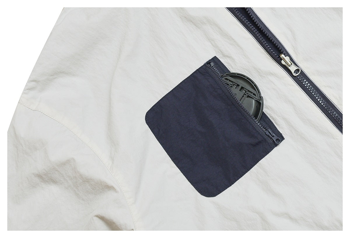 Close-up of a white garment with a dark zipper and a dark zippered pocket.