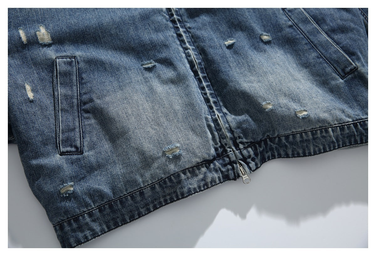 Close-up of the denim jacket lower front, showing slanted pockets, distressed marks, and hem zipper.