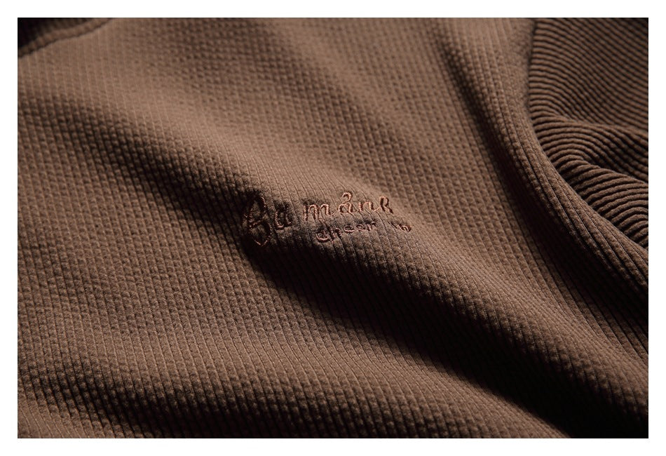 Close-up of small tonal embroidered lettering on the chest of the brown hoodie.
