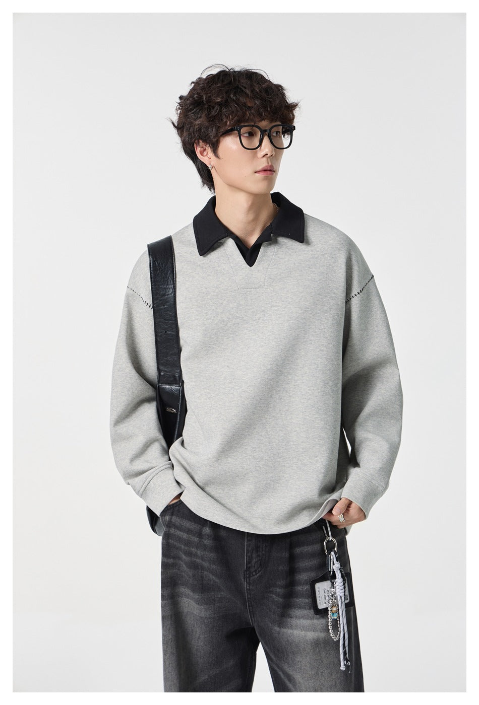 Close view of a model wearing a light gray pullover with a contrasting black collar and stitched shoulders.