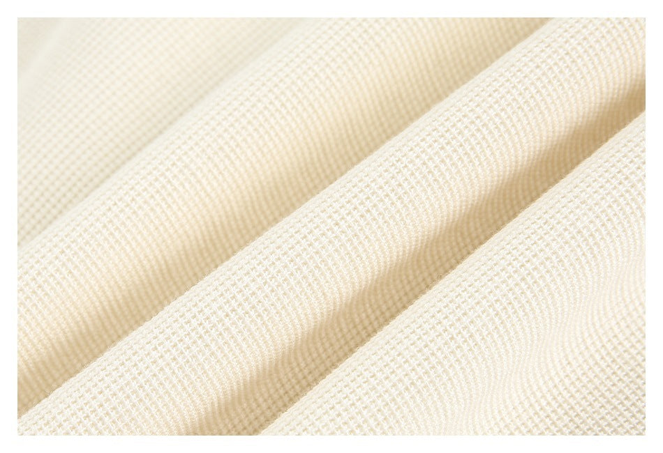 Macro view of the cream garment's raised, grid-like fabric texture.