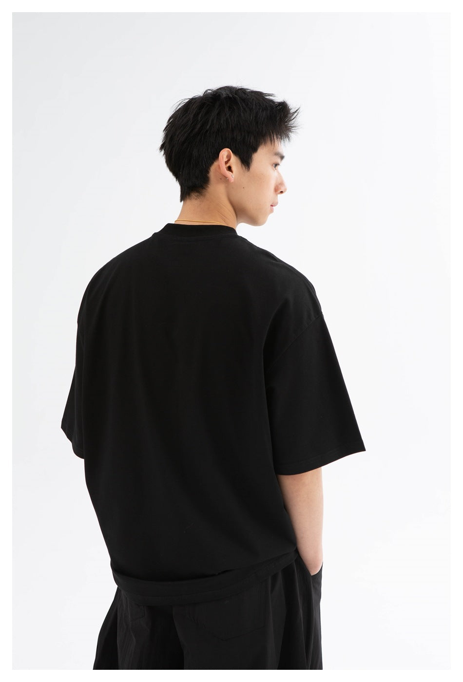 Model shown from behind wearing a plain black oversized short-sleeve T-shirt.