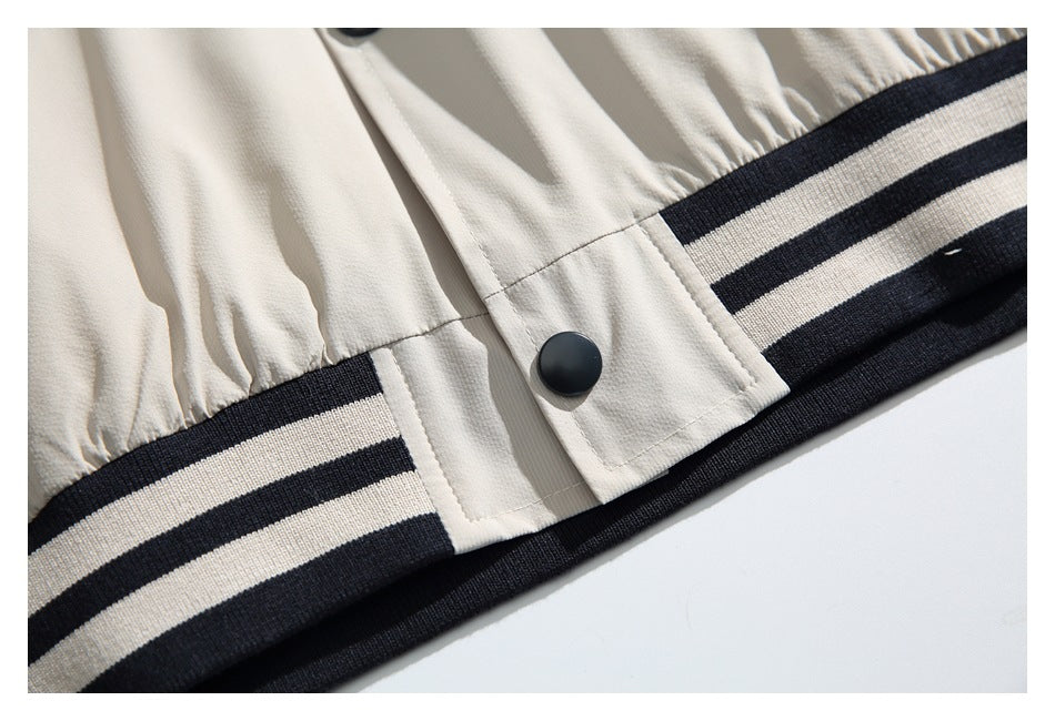 Close-up of an ivory jacket hem with a black snap and dark-and-ivory striped ribbed trim.