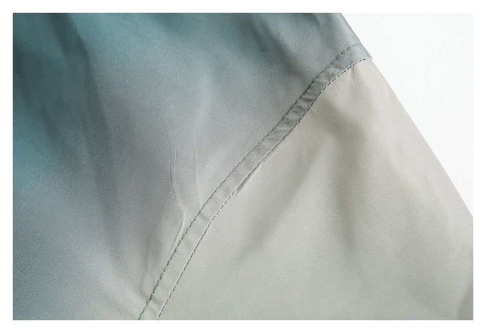 Close-up of a teal garment panel joined to a light gray panel with a curved stitched seam.