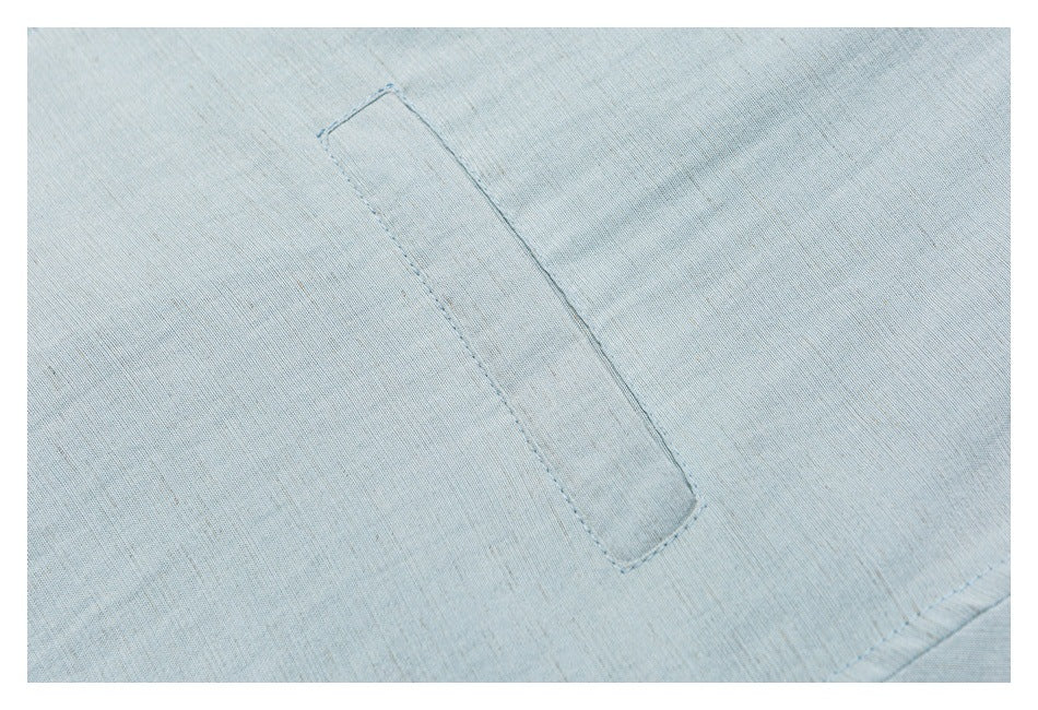 Close-up of a stitched rectangular pocket on pale blue fabric.