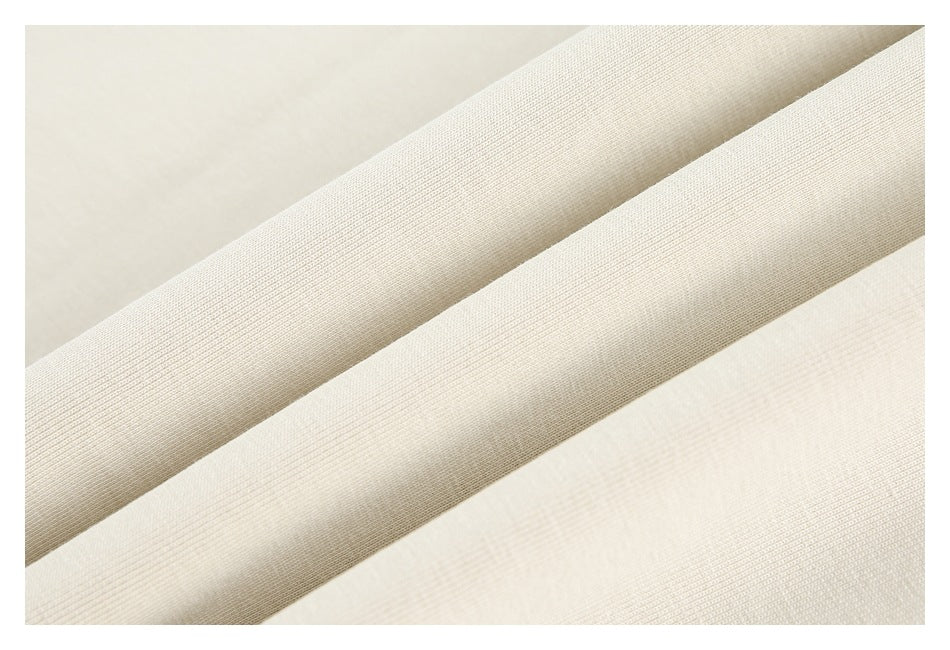 Close-up of cream fabric folded into diagonal ridges, showing its woven texture.
