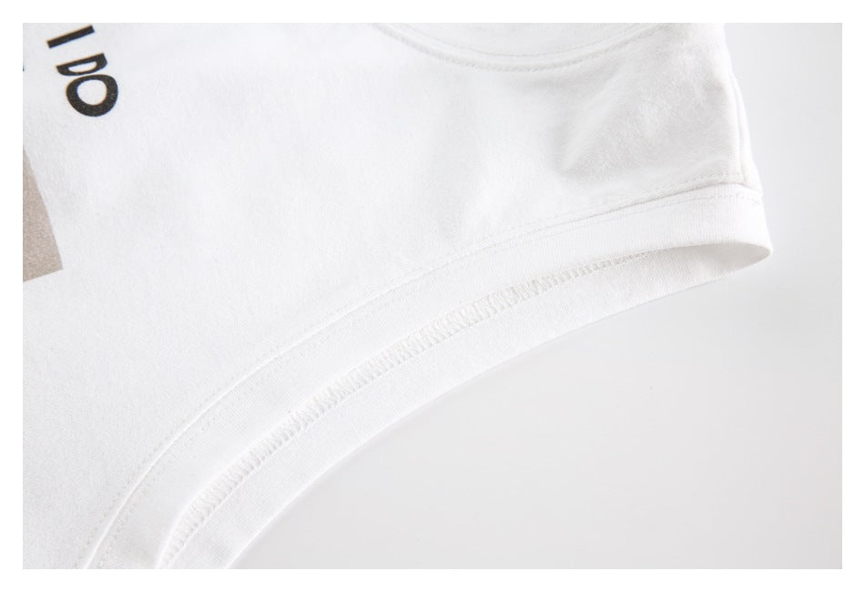 Close-up of the white top’s curved armhole edge and stitching, with a small part of the front print visible.