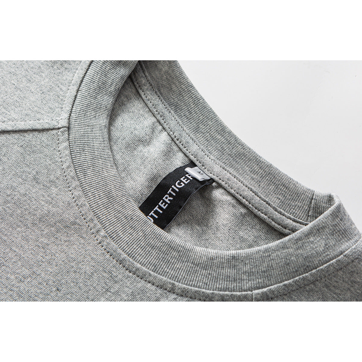 Close-up of a heather-gray T-shirt’s ribbed crew neck and inner sewn label.
