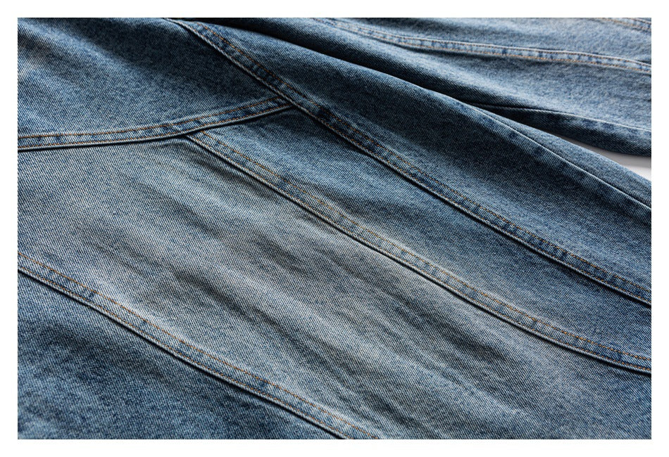Close-up of blue denim panels with diagonal orange topstitched seams.