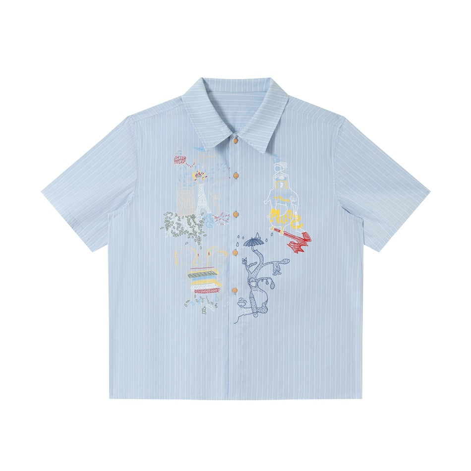 Light blue striped short-sleeve shirt with colorful line-art embroidery on the front, flat lay