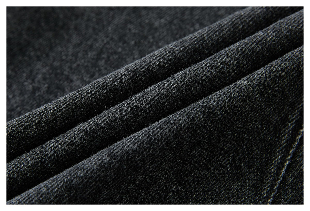 Macro view of dark charcoal denim fabric folded into ridges, showing its woven texture.