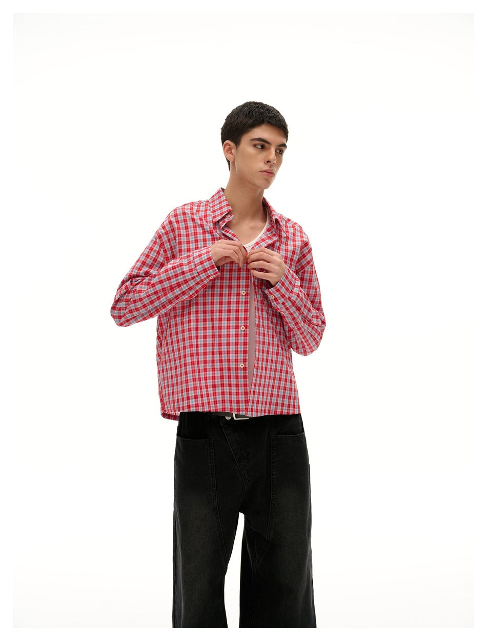 Closer view of a model adjusting the collar of a red-and-white plaid button-up shirt over a white top.