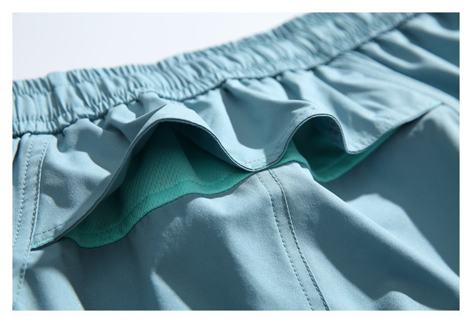 Close-up showing the ruffled edge and teal mesh lining beneath the elastic waistband of light blue shorts.
