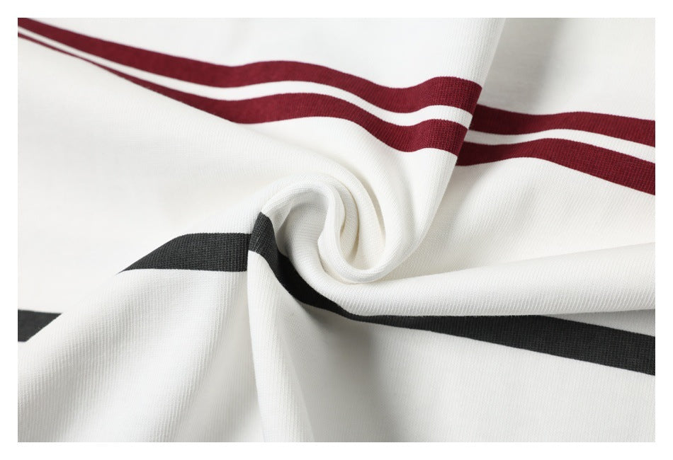 Close-up of white striped fabric twisted into folds, showing burgundy double stripes and a black stripe.
