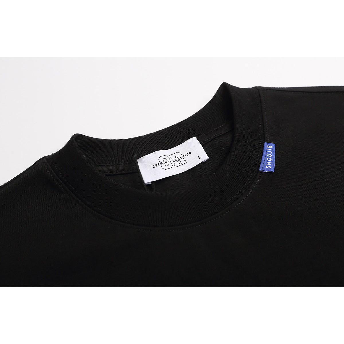 Close-up of a black crew-neck T-shirt collar with a white neck label and a small blue side tag.