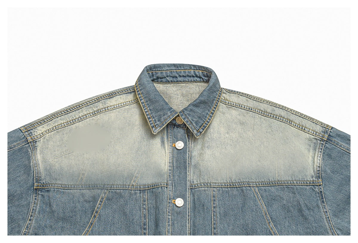 Cropped front view of a two-tone washed blue denim jacket with a pointed collar, metal buttons and a blurred oval chest
