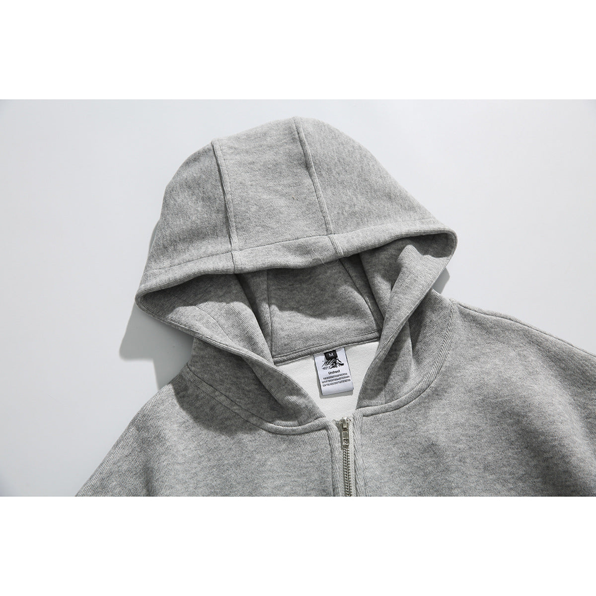 Close-up of a light gray zip-up hoodie showing its hood, neckline, and center zipper.