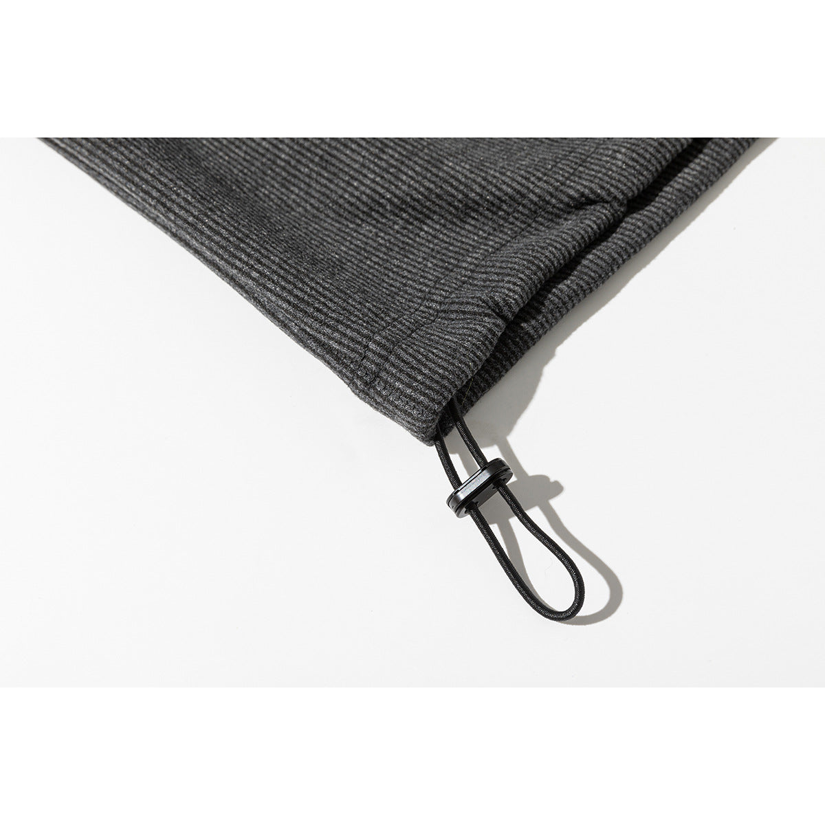 Close-up of a charcoal gray sweatshirt hem with an adjustable black cord and toggle.