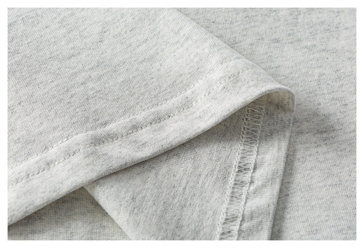 Close-up of a heather-gray garment's folded hem and overlocked seam.