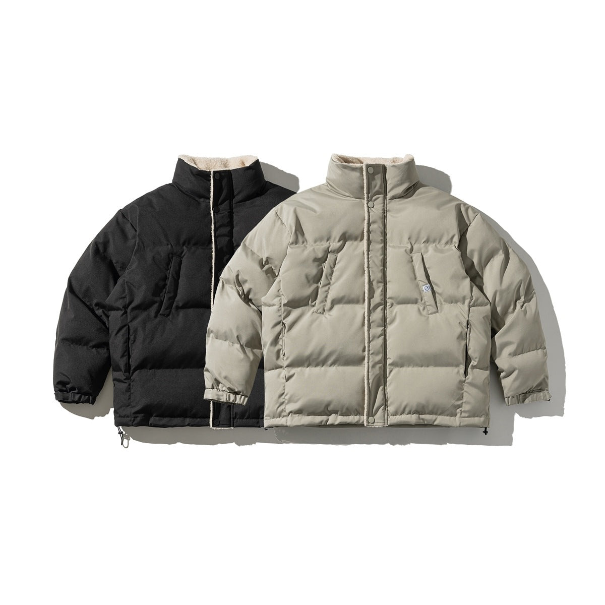 Front view of padded snap-front jackets in black and light gray, with high collars and horizontal quilting.