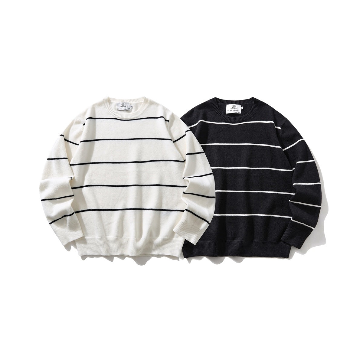 Two striped crew-neck sweaters shown from the front: ivory with black stripes and black with ivory stripes.