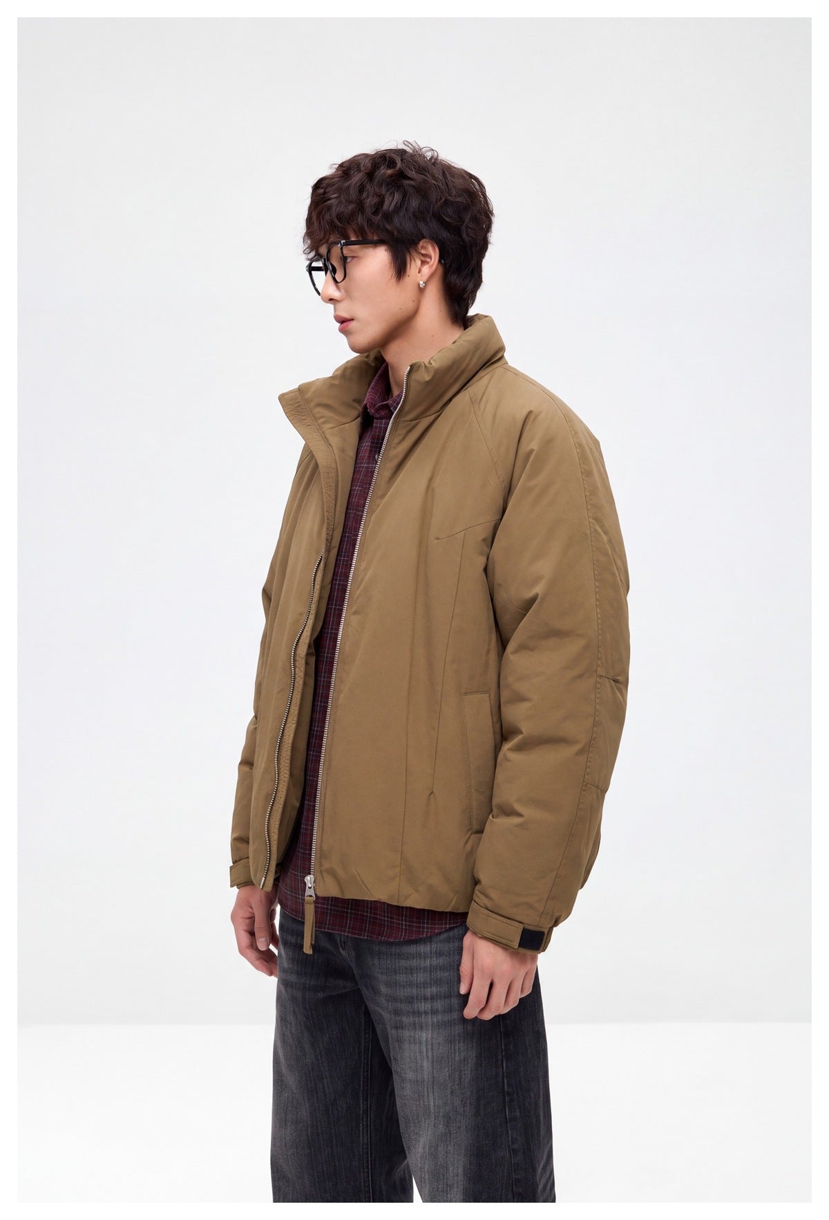 Side view of a model wearing a brown zip-front jacket with a raised collar and burgundy plaid shirt.