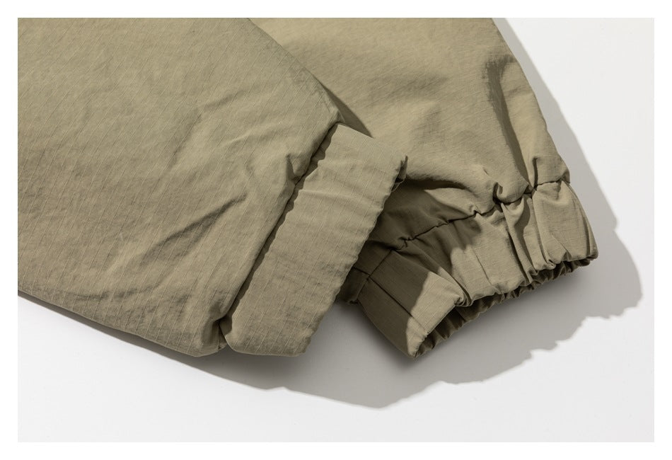 Close-up of a khaki garment with a gathered elastic cuff and fine grid texture.
