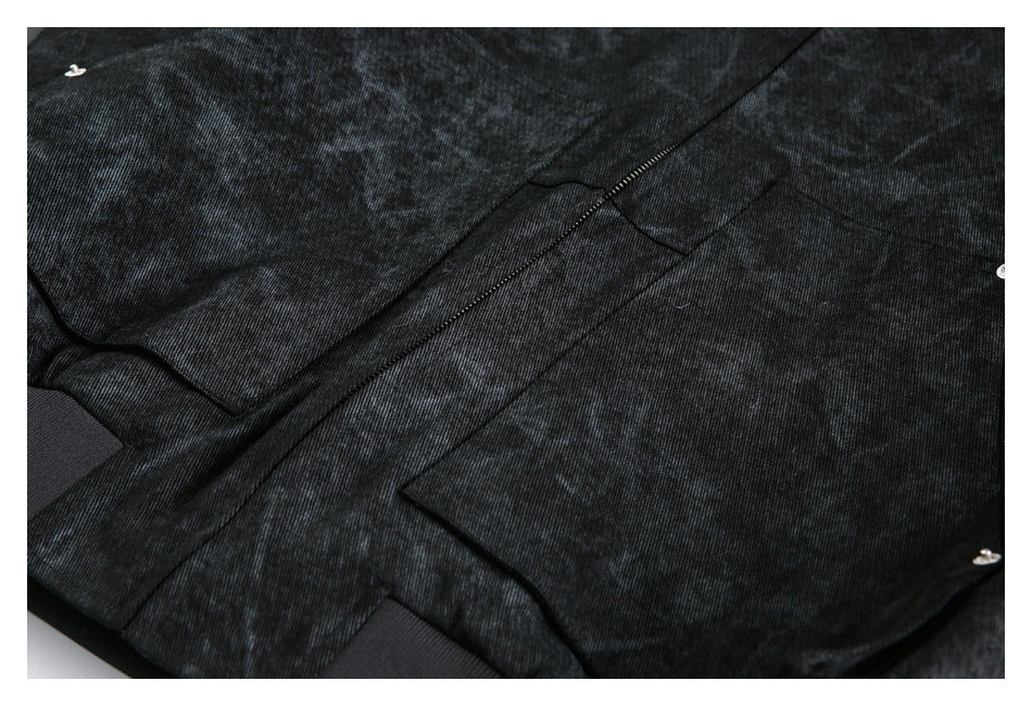 Close-up of the jacket front showing a pocket, zipper, seams and metal snaps on dark mottled fabric.