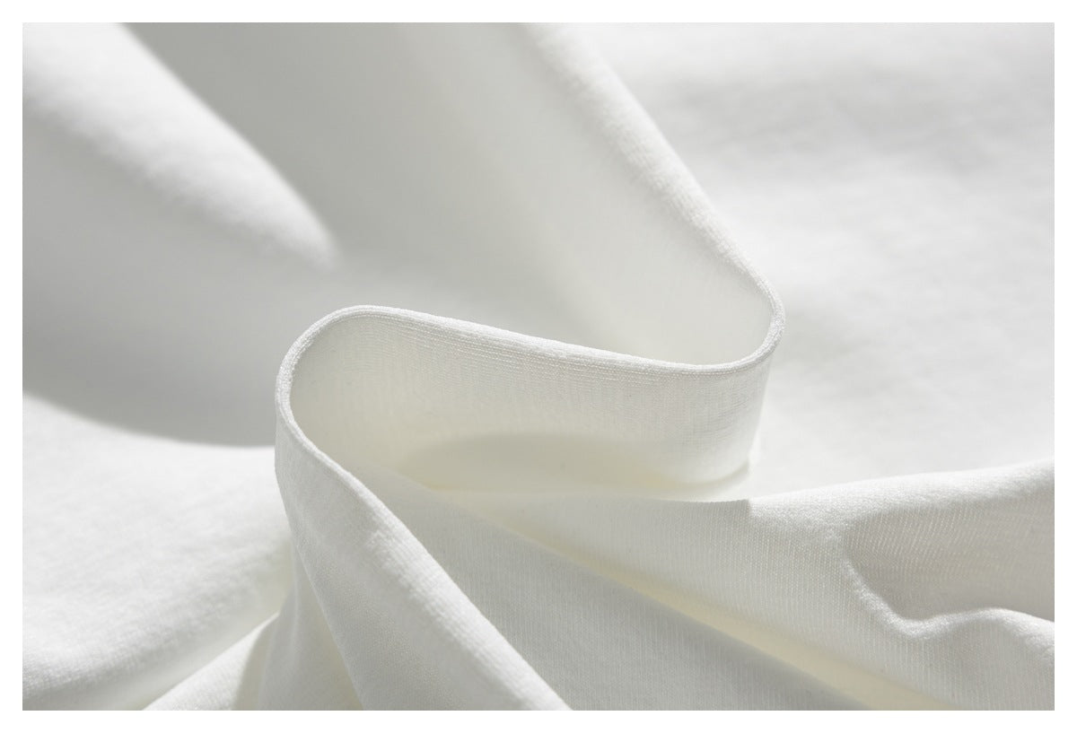 Close-up of white fabric folded into soft curves, showing its fine woven texture.