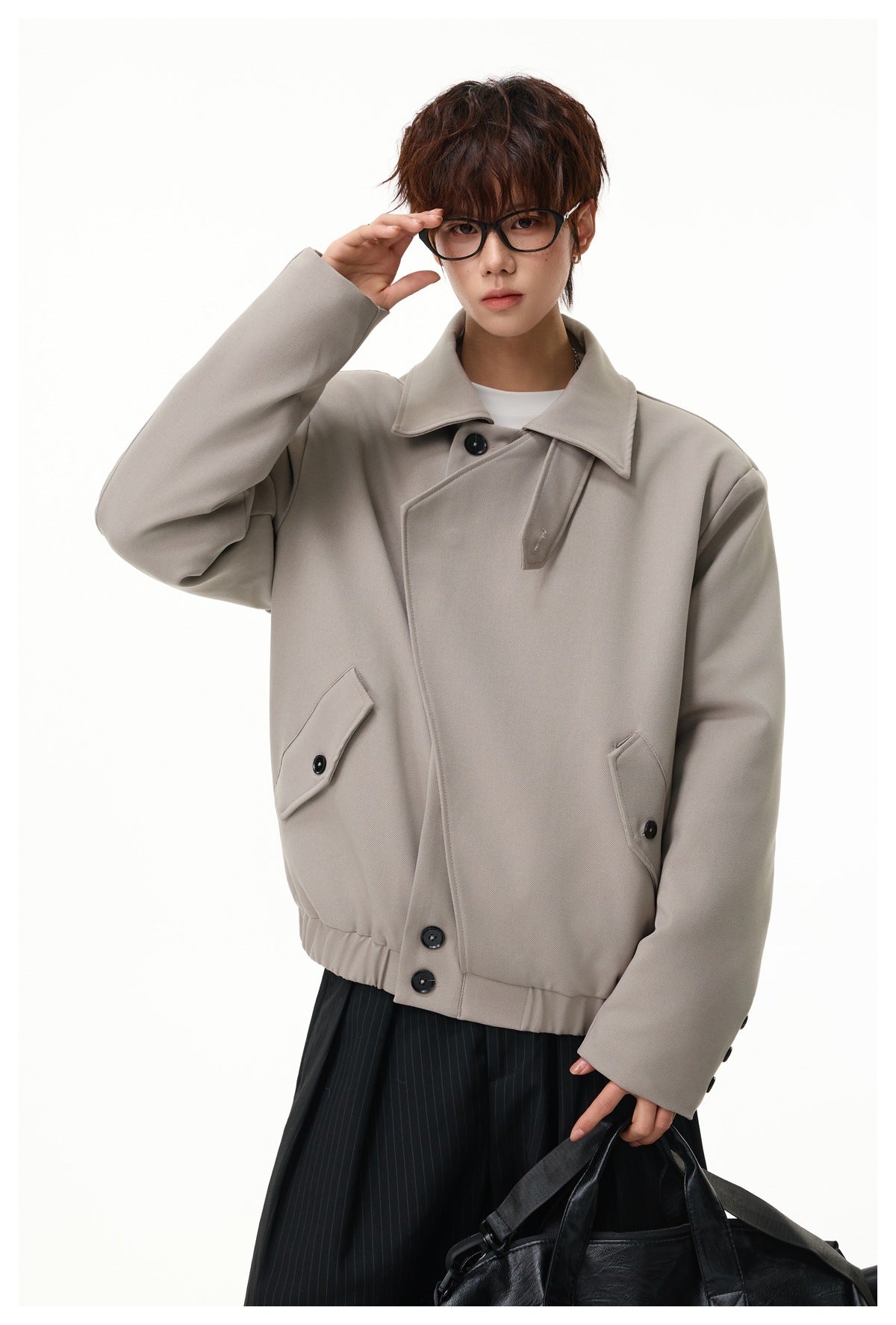 Close-up of a model in the gray khaki jacket showing the collar, asymmetric buttons, flap pockets and elastic hem