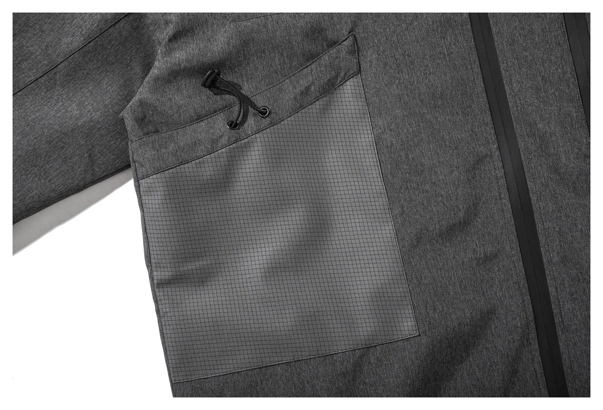 Close-up of a large grid-patterned pocket on the charcoal jacket, with a drawcord at the pocket opening.